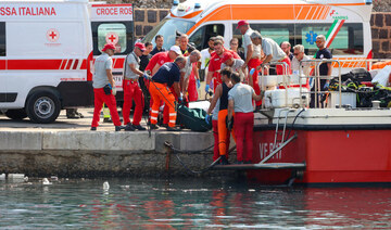 Italian firefighters and health workers carry a body bag with a victim after a sailboat sank off the coast of Porticello.