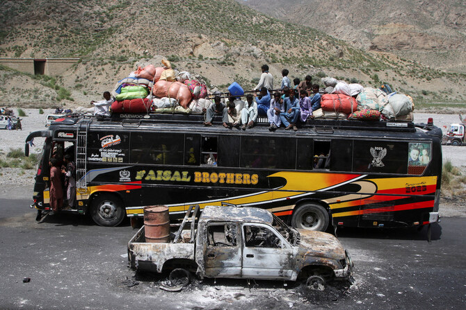 A bus drives past a damaged vehicle, a day after separatist militants conducted deadly attacks, in Balochistan.